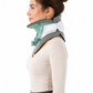 A woman in profile wearing a gray and white cervical collar with a translucent green neck portion, shown against a plain white background.