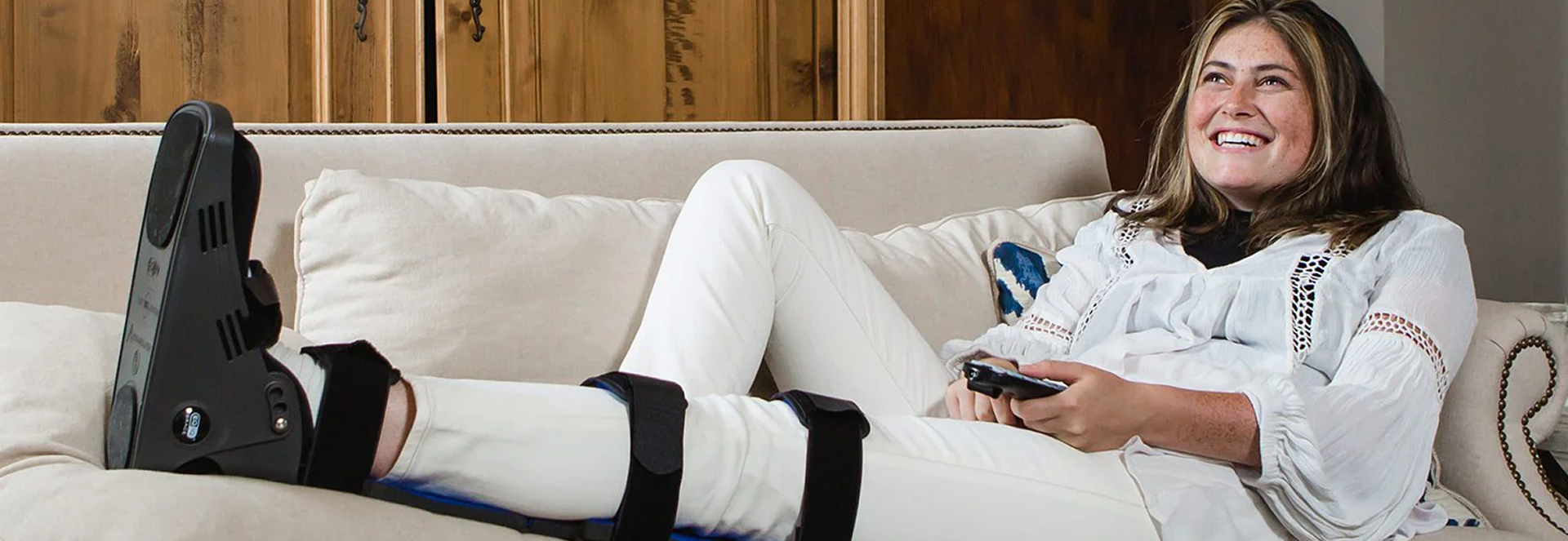 Woman sitting on a couch with a cast on her leg, holding a remote control.slider_item_nbANc6